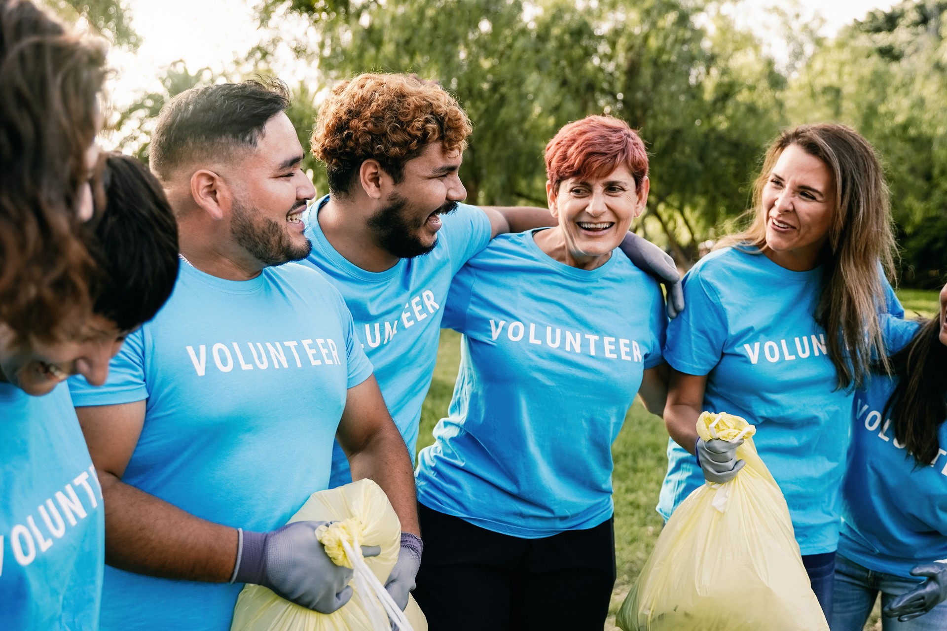 Environmental activists picking up garbage trash at park city. Group of multiracial volunteers cleaning and doing community service